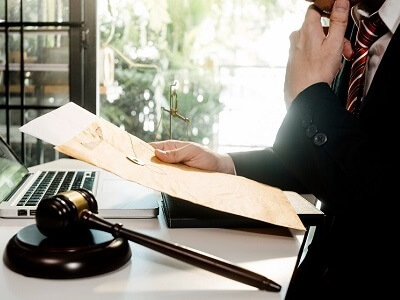 איש לבוש בחליפה ובעניבה קורא מסמכים מול מחשב נייד